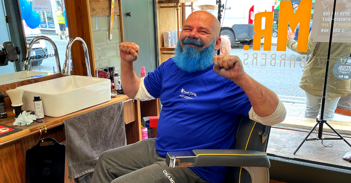 A man with a blue beard sitting at the salon