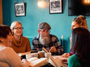 Five Ways to Wellbeing 2 A group of people sitting in a cafe and discussing about a book