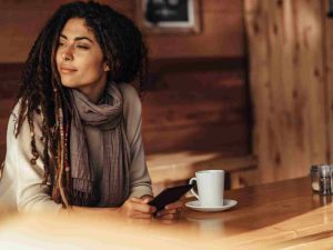 Five Ways to Wellbeing 4 A woman sitting with a cup in her hand looking outside