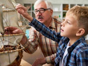 Five Ways to Wellbeing 5 A boy and a elderly man building a sail boat model