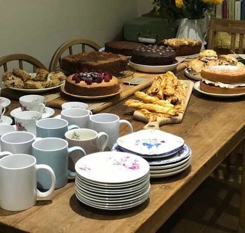 A wooden table with mugs, plates and cakes