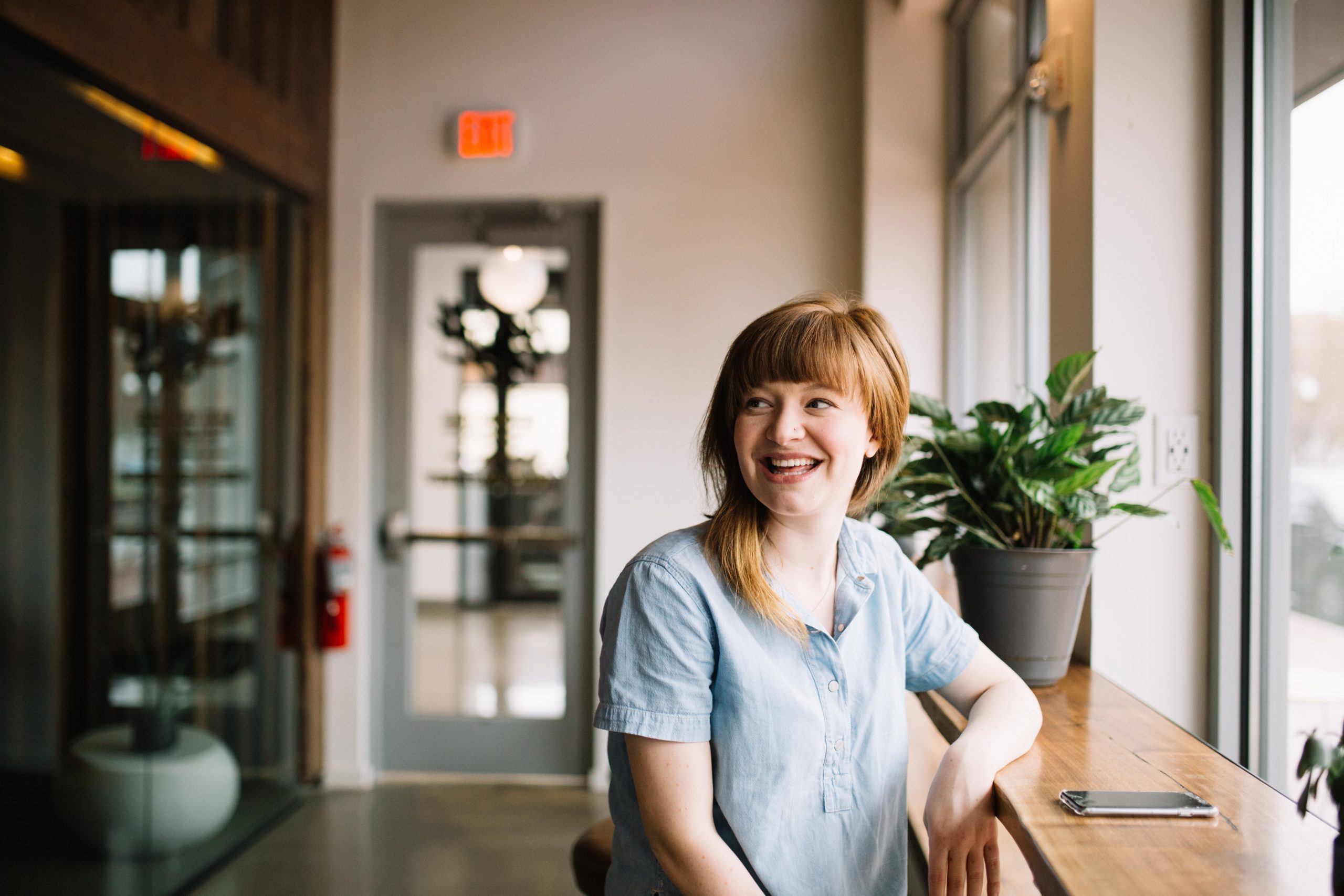 Woman sat at a high wooden table smiling