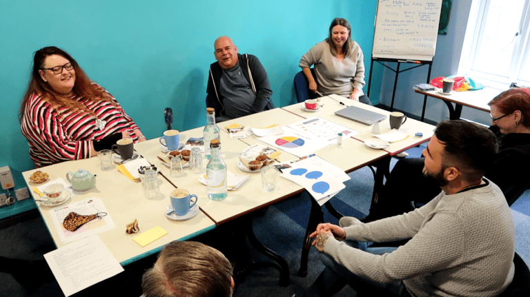 Group of people sat at a table in a room with a blue wall