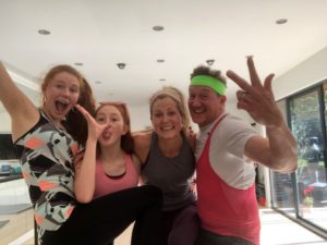 3 women and a man in a kitchen in sports gear smiling