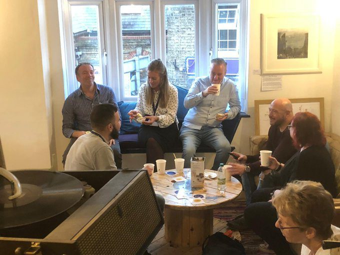 A group of men and women drinking hot drinks and talking