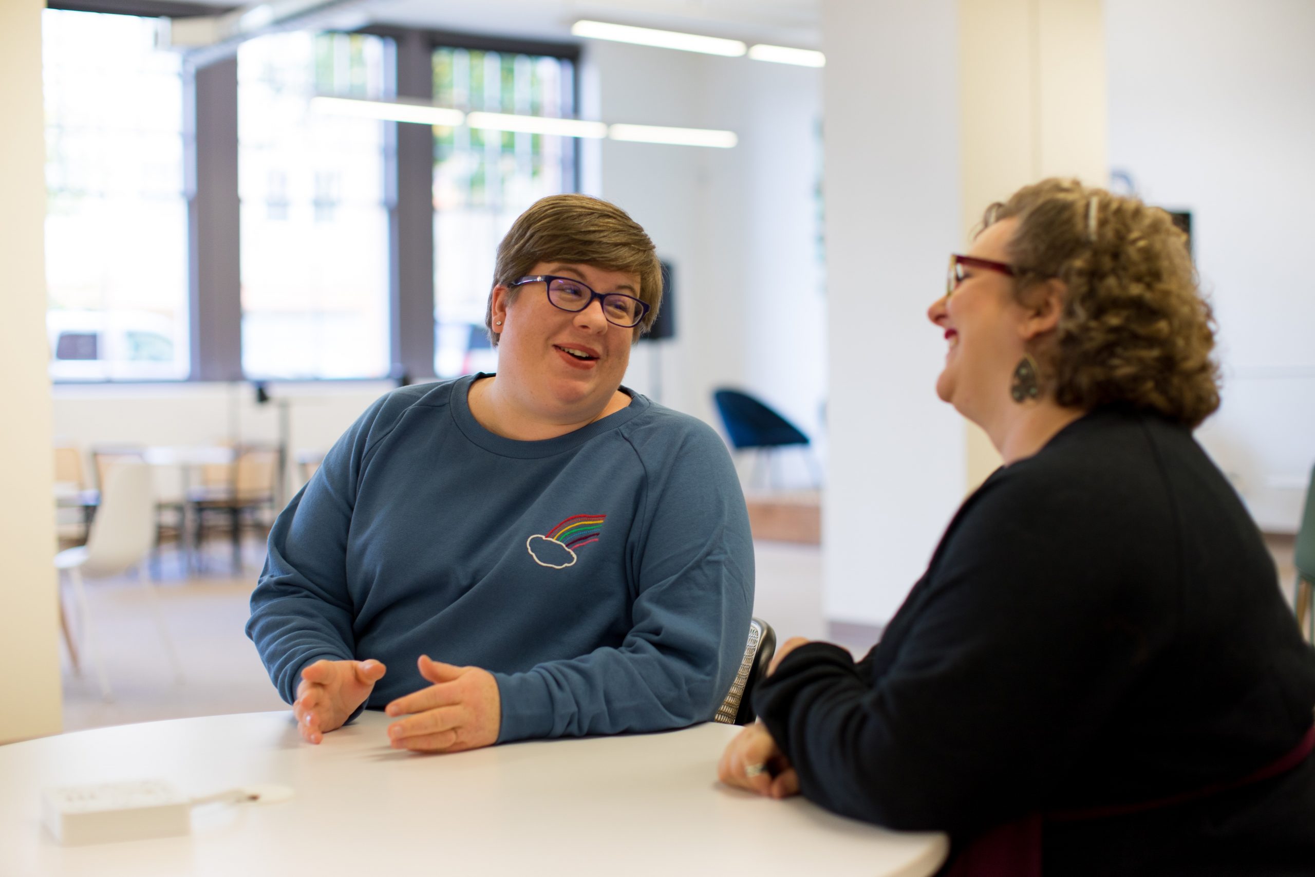 Two women talking to each other sat at a table