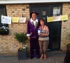 A man and woman in fancy dress in front of a front door with a washing line with signs saying CPSL Mind Mental Health Awareness Week
