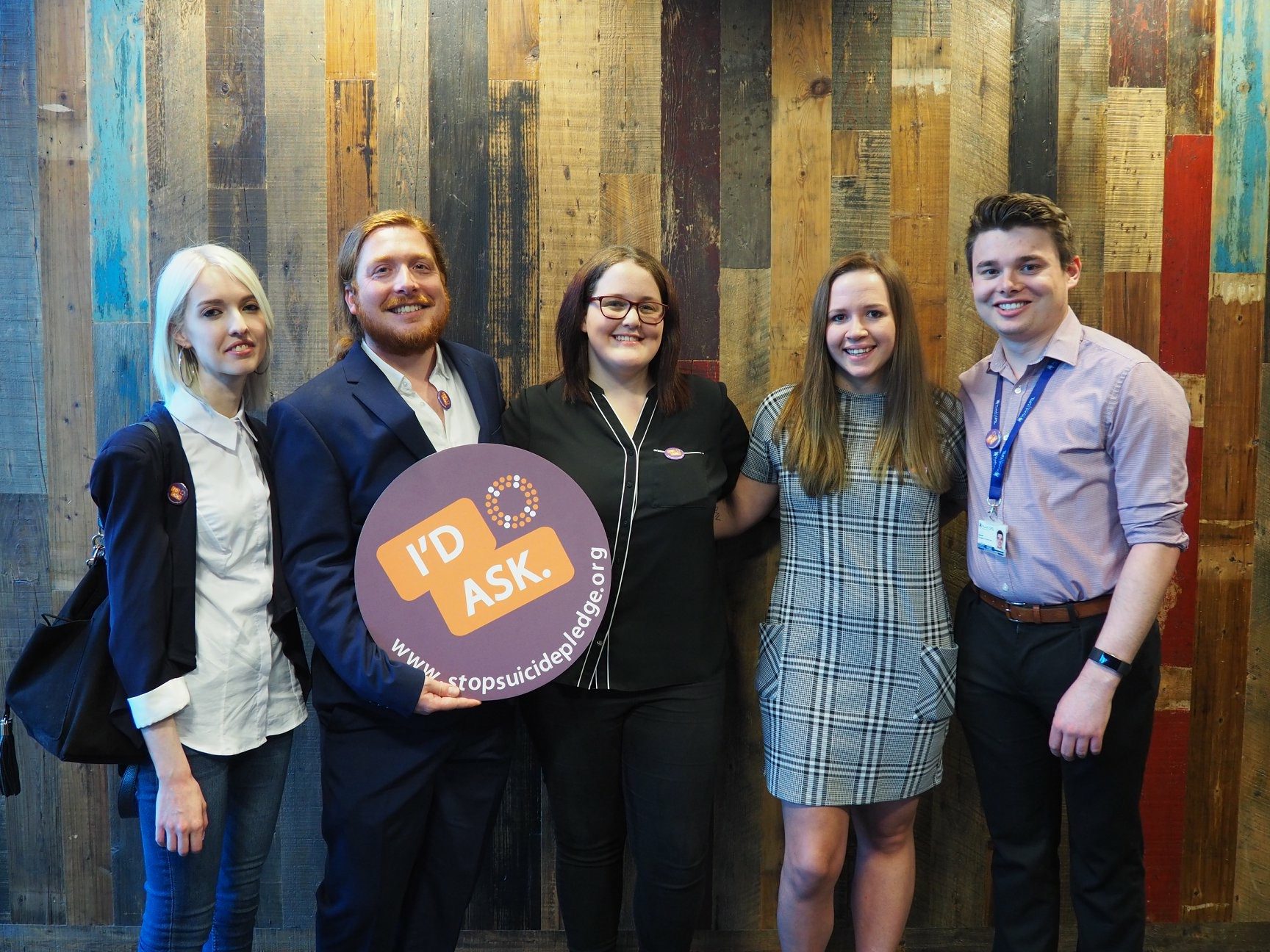 A group of people standing with the STOP Suicide round banner