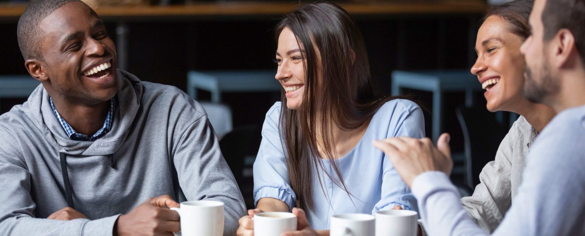 Multiracial friends girls and guys having fun laughing drinking coffee