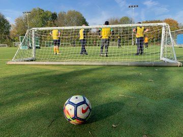 A football behind a football net with players in front of the net