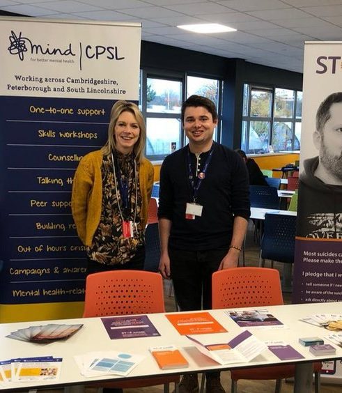 A man and woman standing in front of two banners for CPSL Mind and Stop Suicide