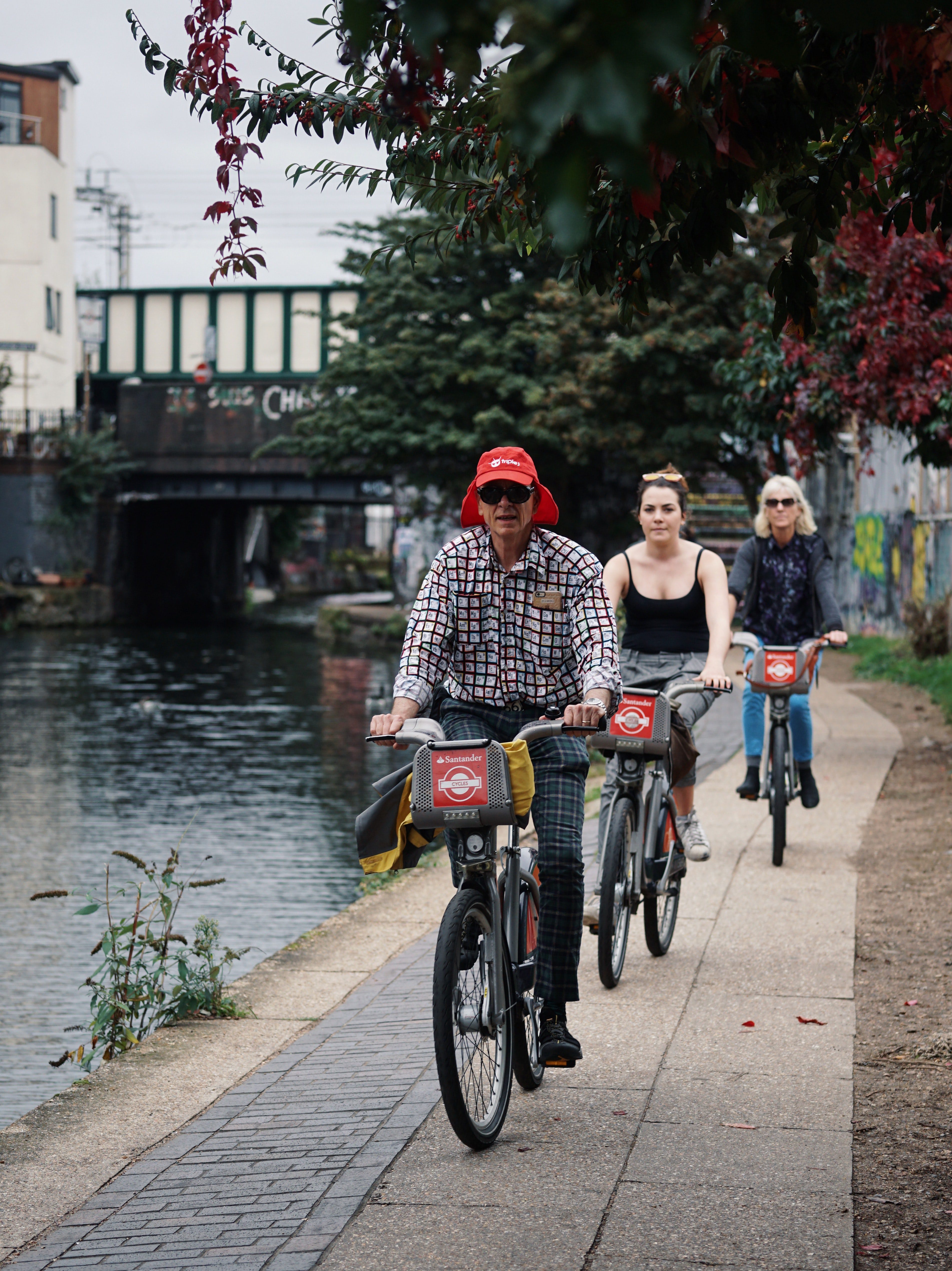 Three people on Santander bikes riding next to a river