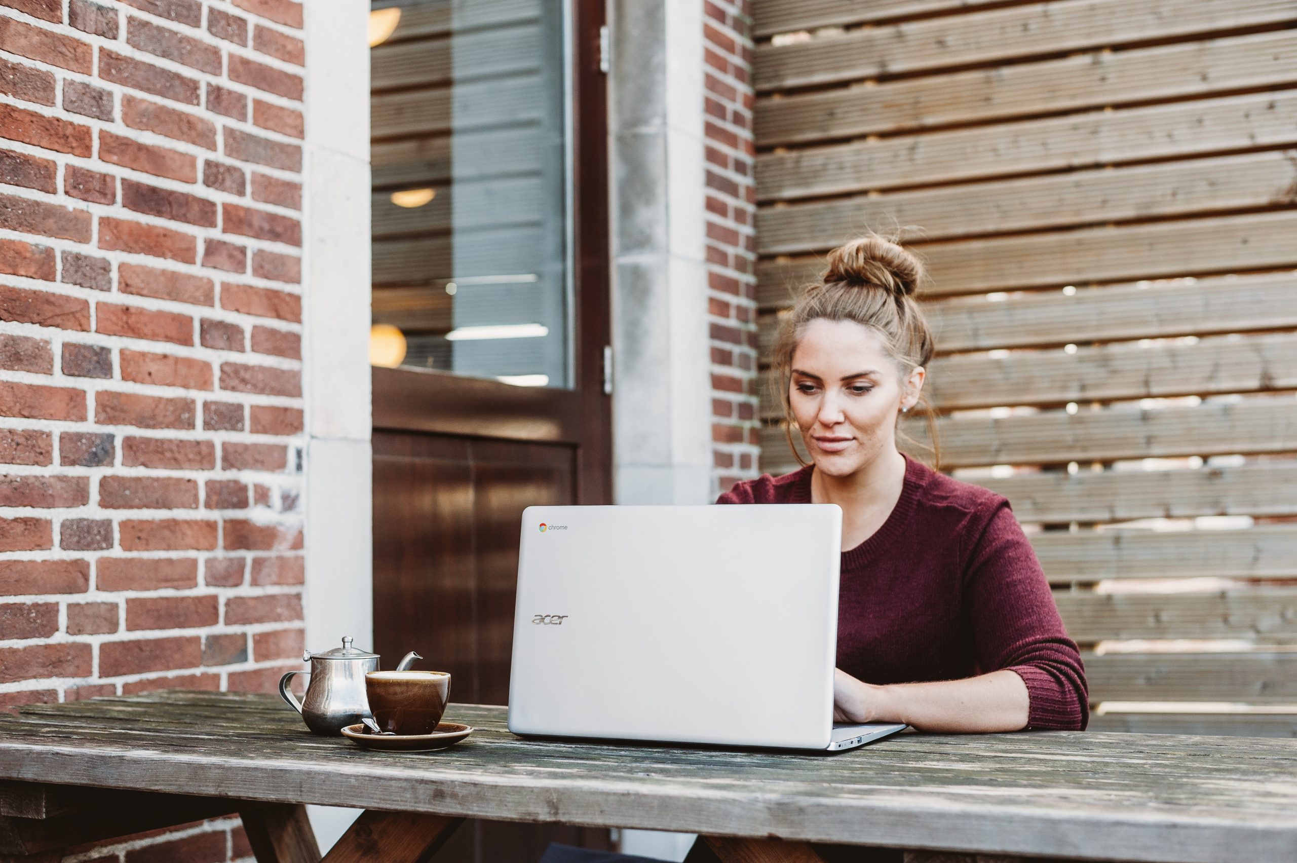 woman sat at laptop on bench in garden