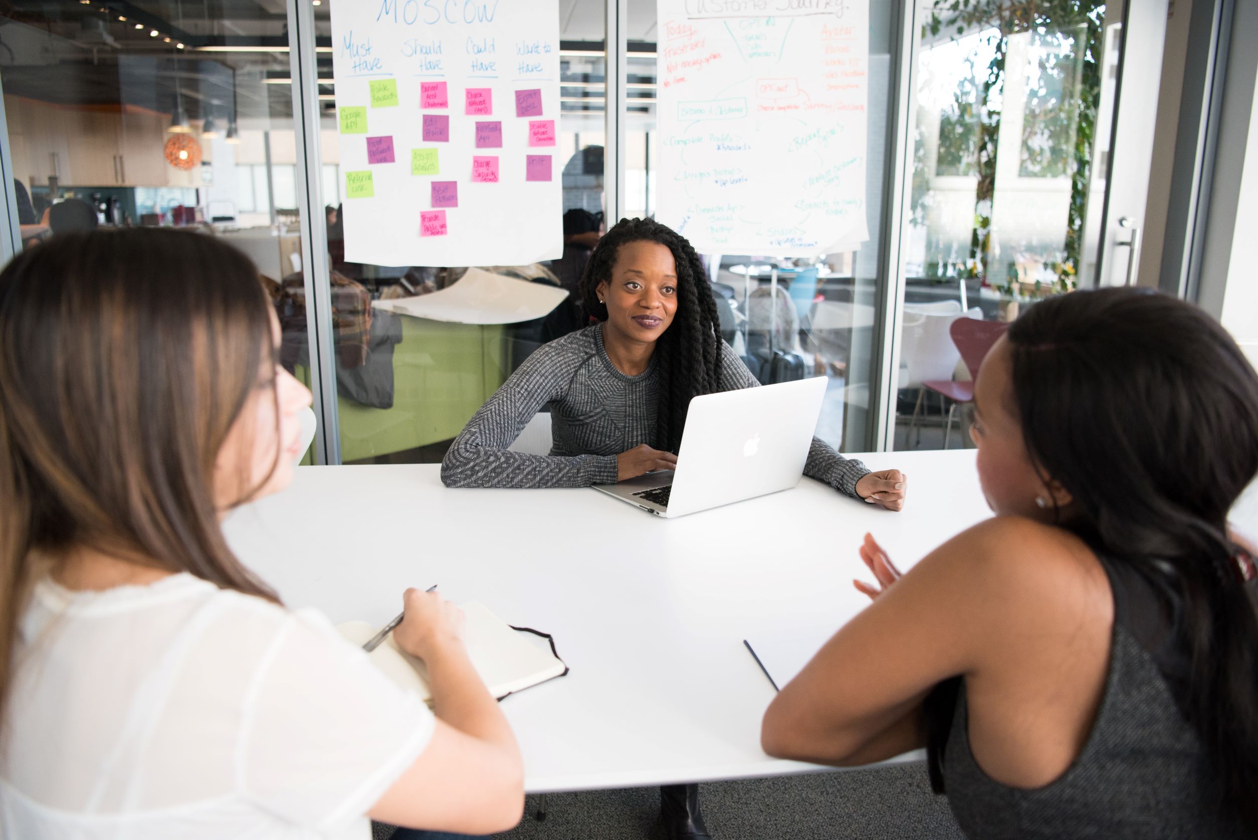 Three women in office talking with laptop and notes