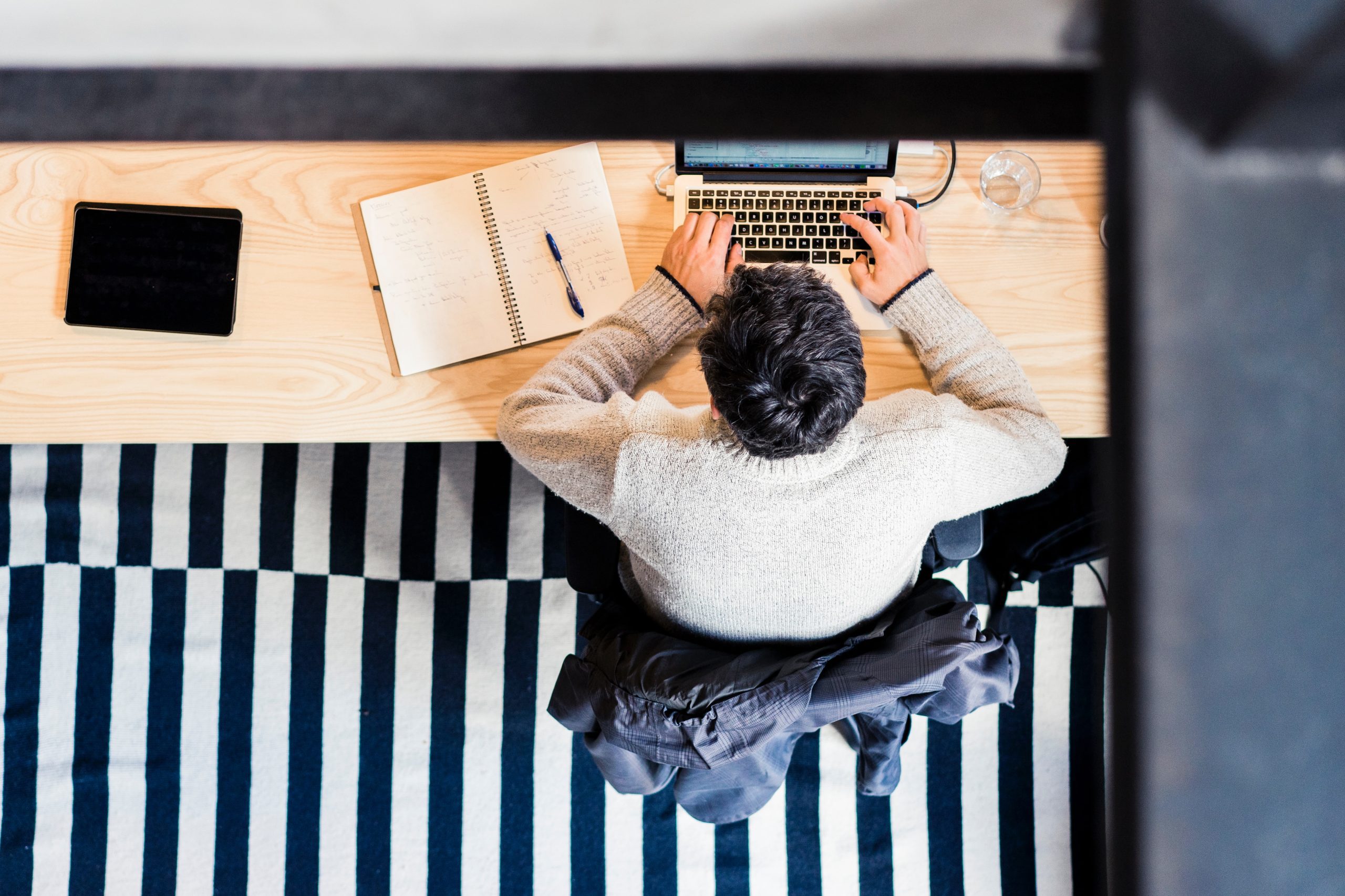 Person on stripped rug in office working on laptop