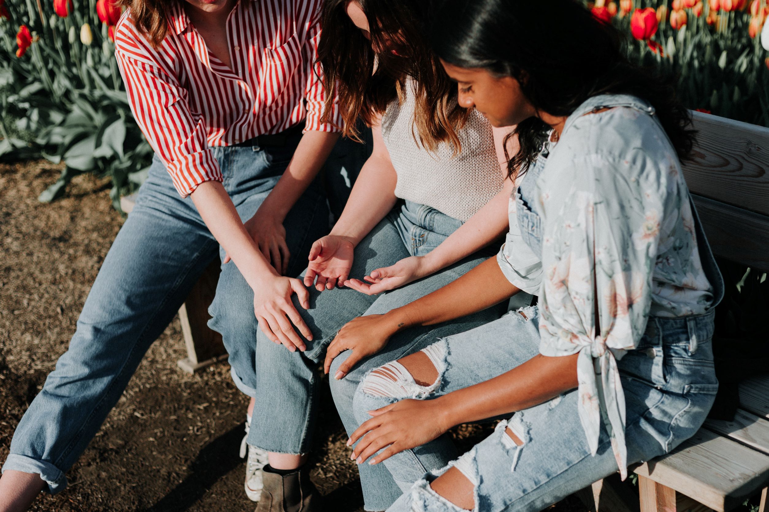 Three women sat on bench consoling woman in middle