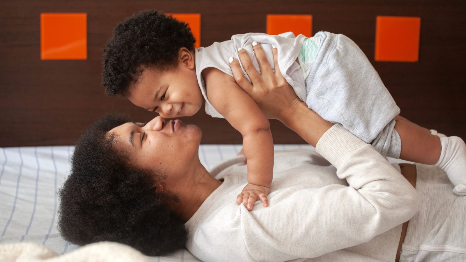 woman laying on bed holding up son