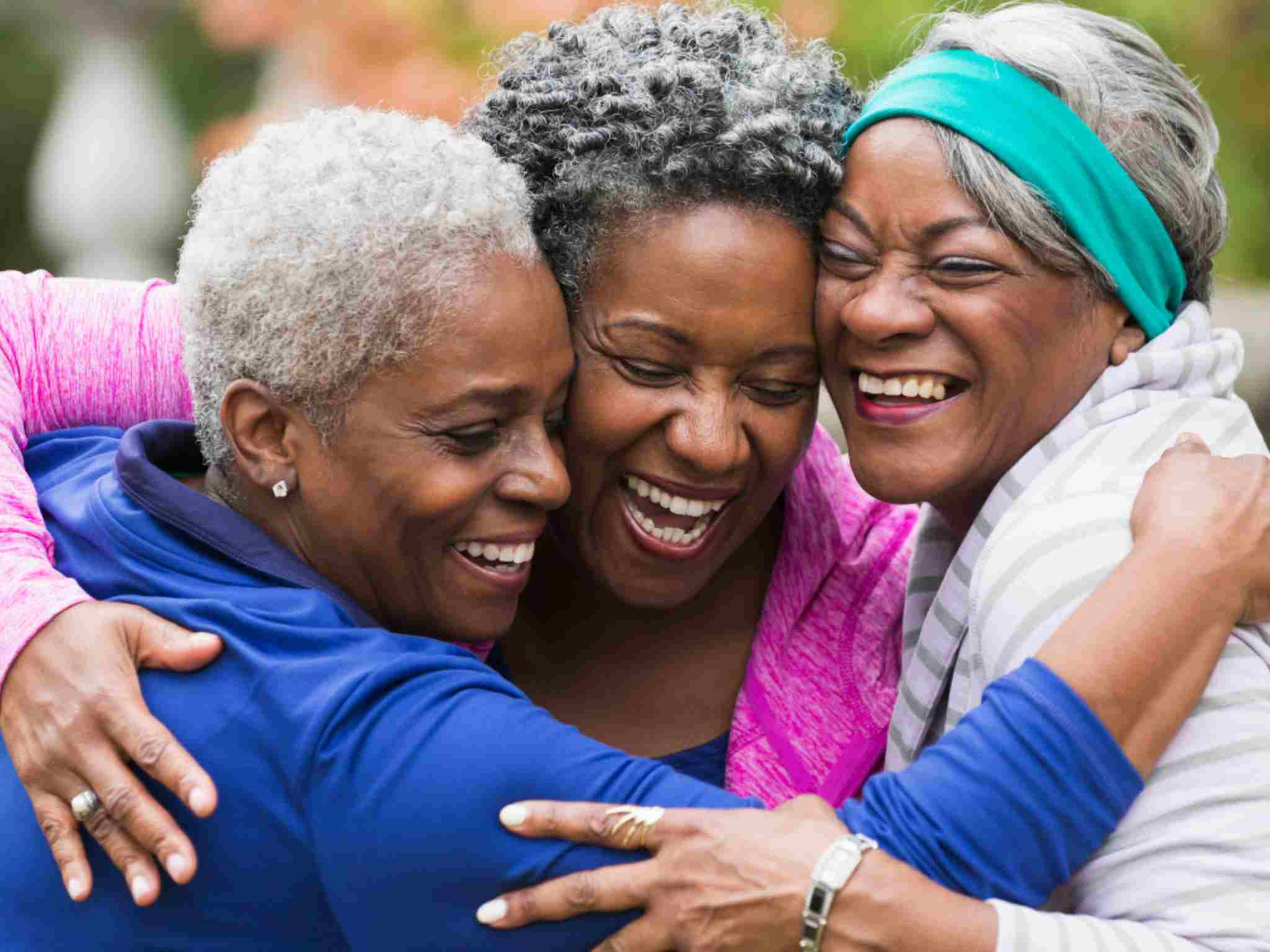 Three women hugging and laughing - donate