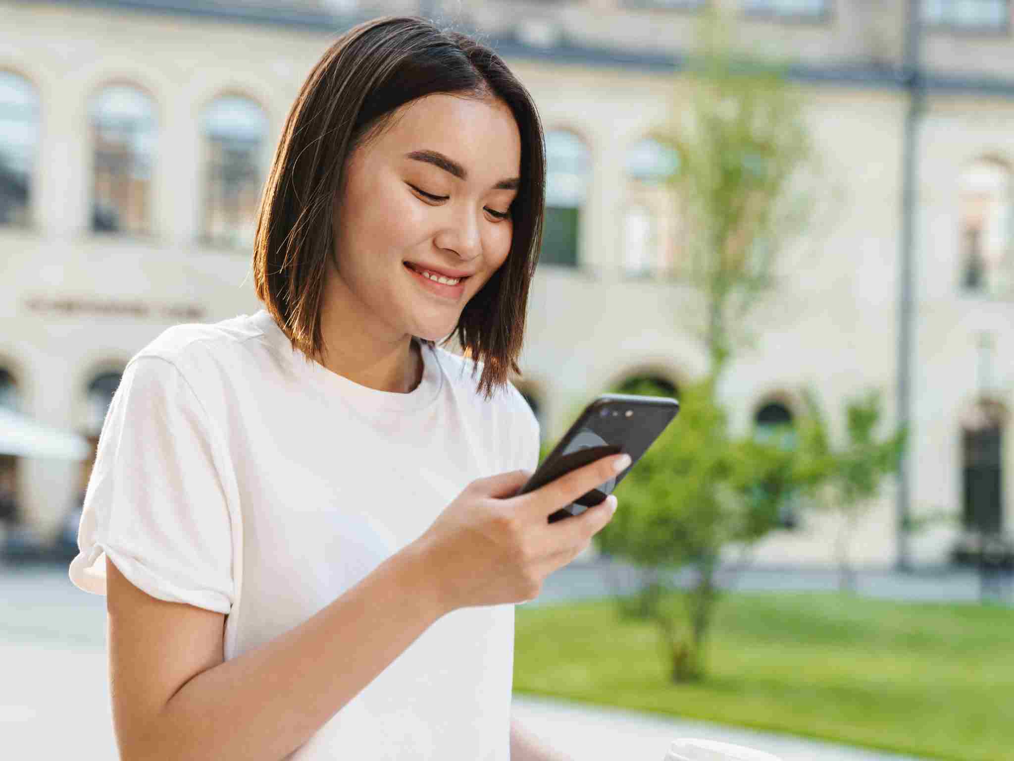 A woman smiling while looking at her phone