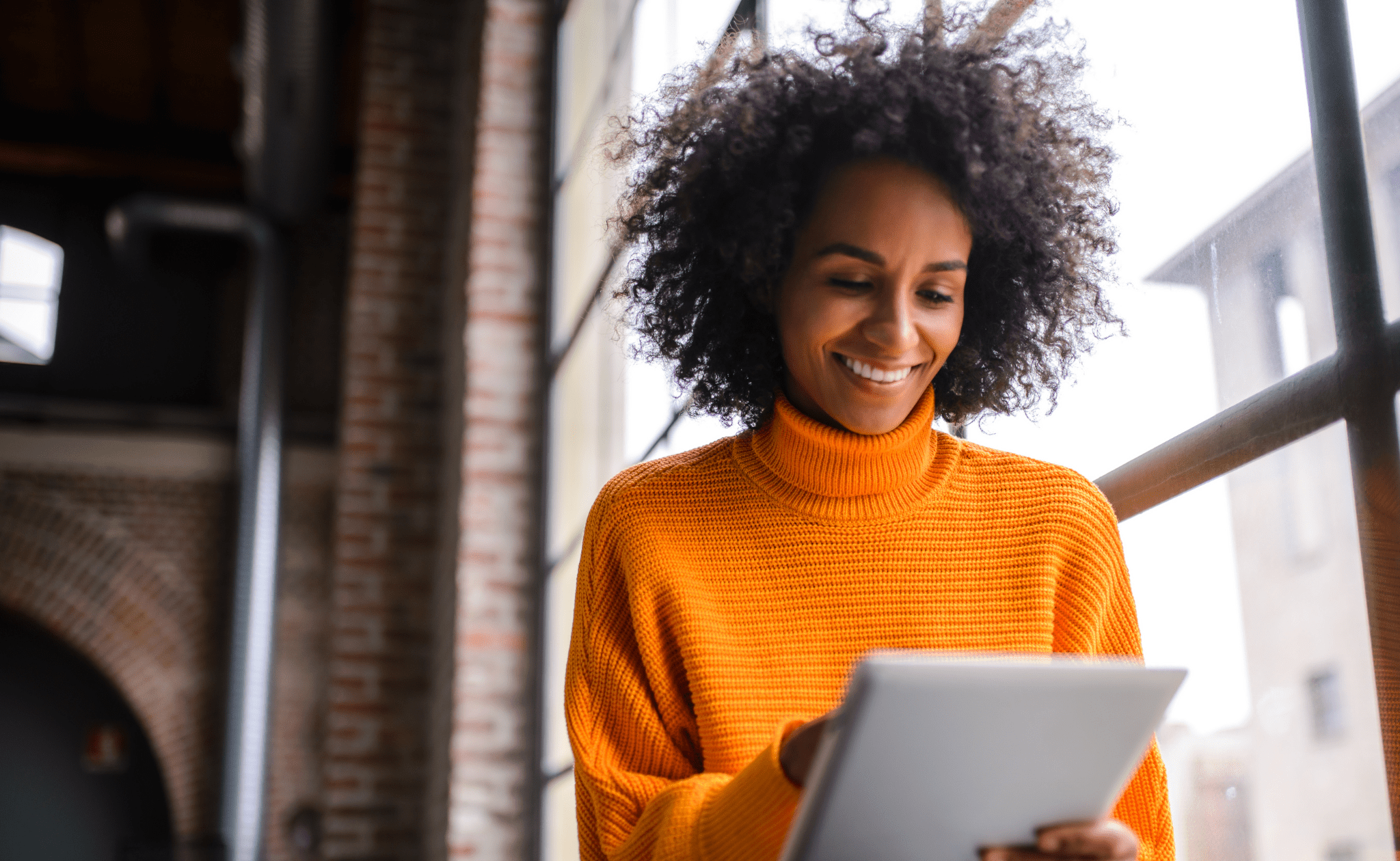 Lady in orange jumper looking at tablet