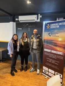 image of two woman and man standing in front of sign at a football club