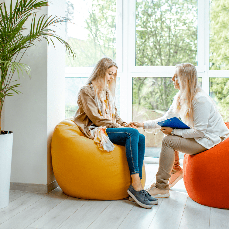 two women sitting on bean bags chatting