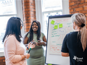 group of three women next to a flip chart talking