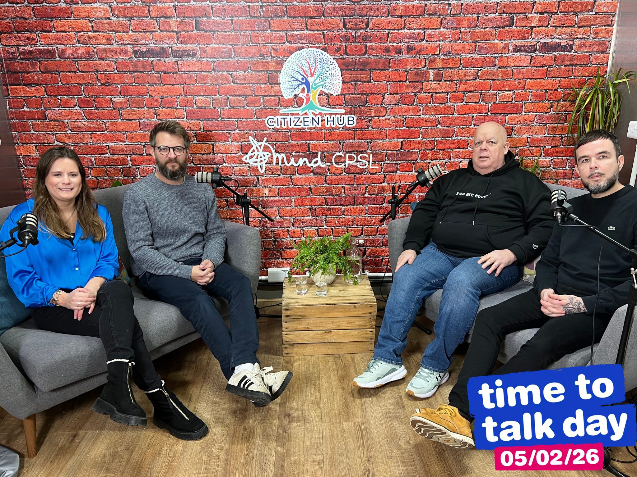 group of three men and one women sitting on sofa with mics