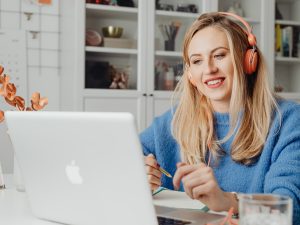 girl with blonde hair on a laptop with orange headphones