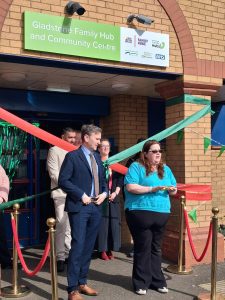 man and woman cutting ribbon outside buildling