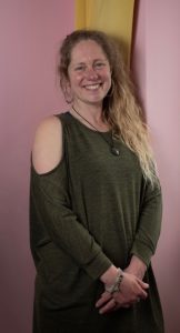 lady with blonde hair smiling against pink wall