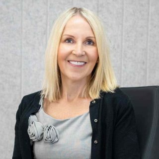 women with blonde hair wearing black cardigan smiling