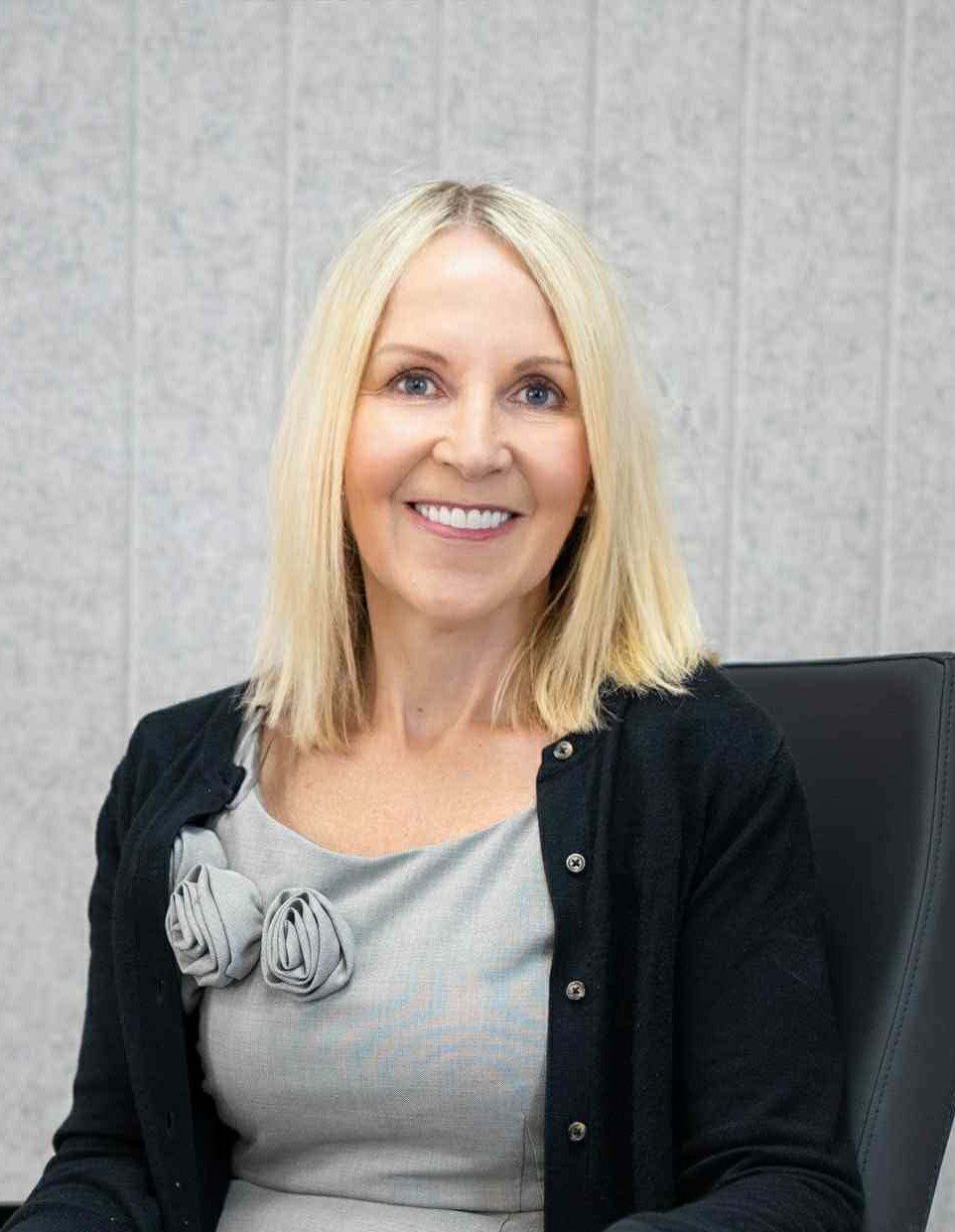 women with blonde hair wearing black cardigan smiling